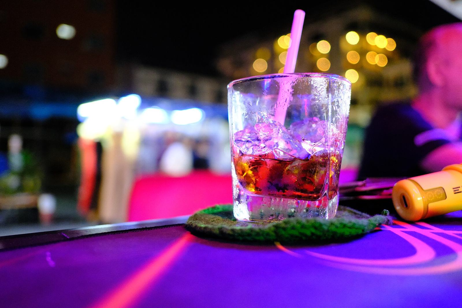 A cocktail on a neon-lit bar counter at night