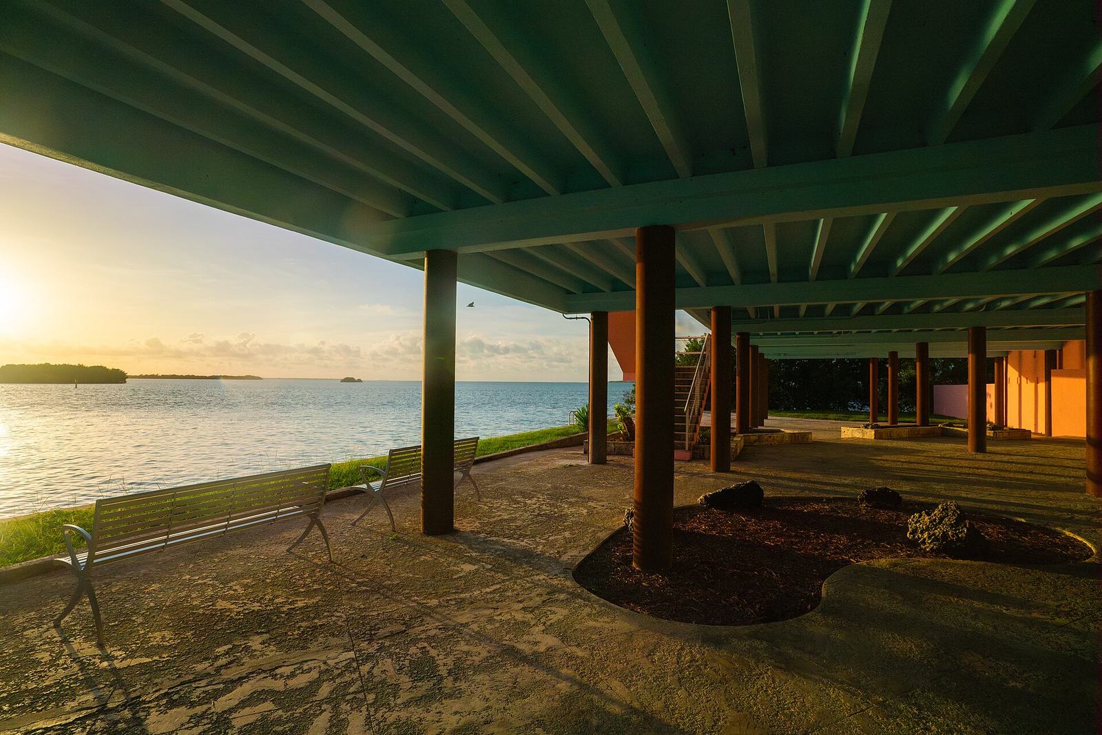 A boardwalk pier over calm Florida bay water at sunset