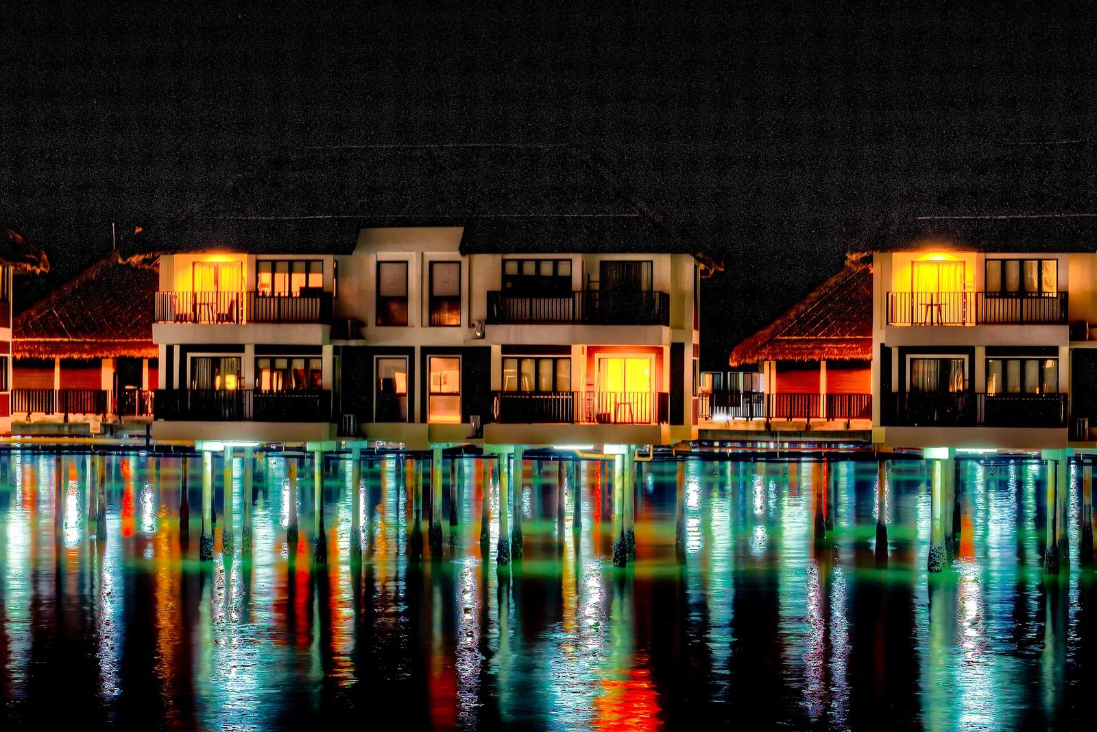 Waterfront homes lit up at night, reflected in the water