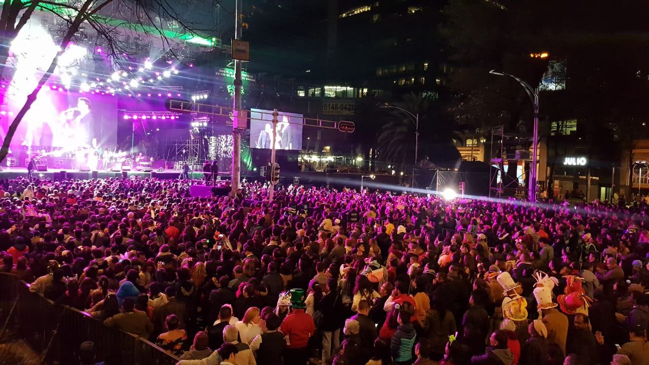 A massive concert crowd under purple stage lights